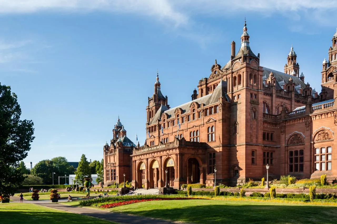 a large brick building with a garden in front of it at Maldron Hotel Glasgow City in Glasgow