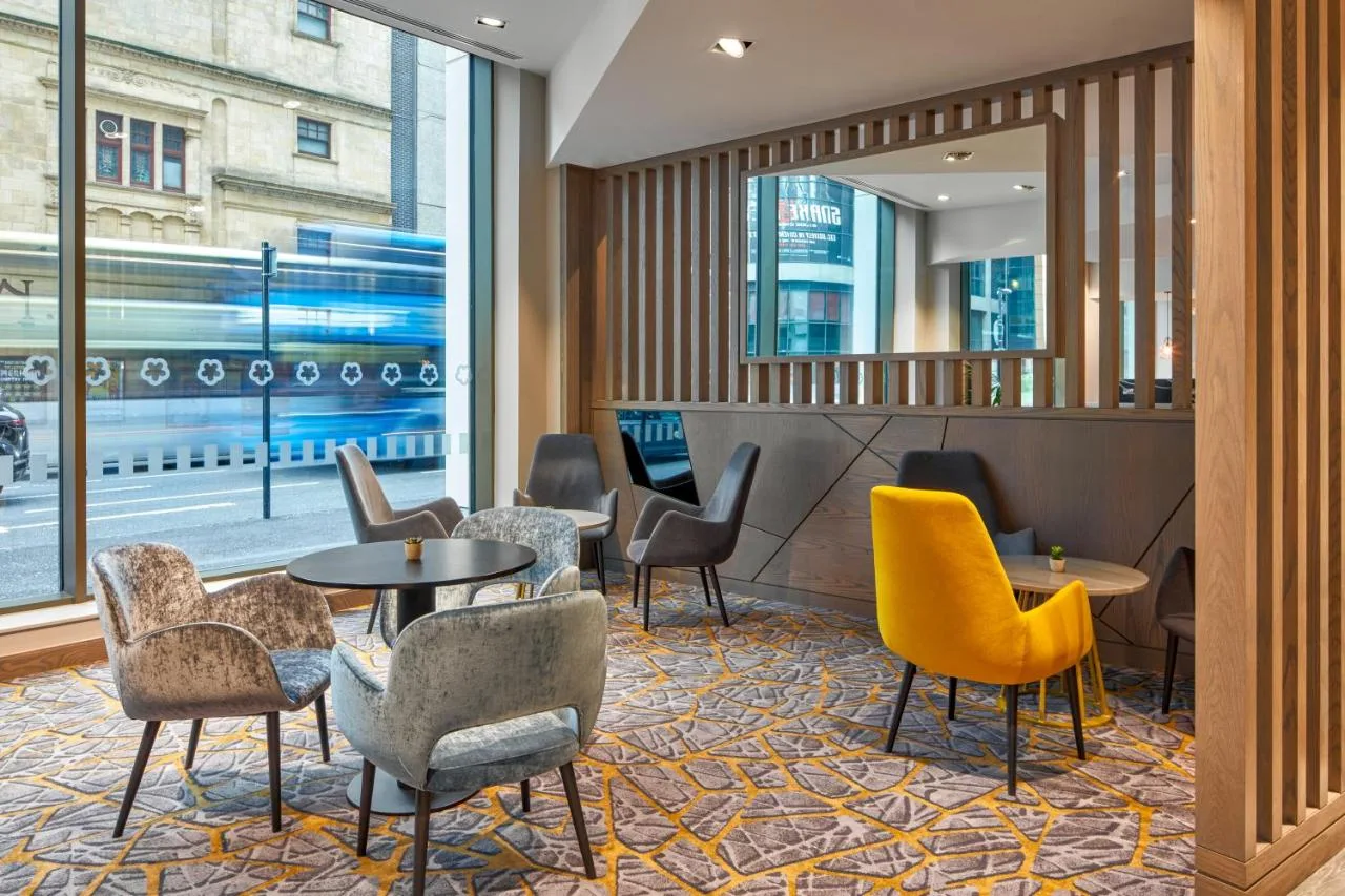 a lobby with chairs and tables and a window at Maldron Hotel Glasgow City in Glasgow
