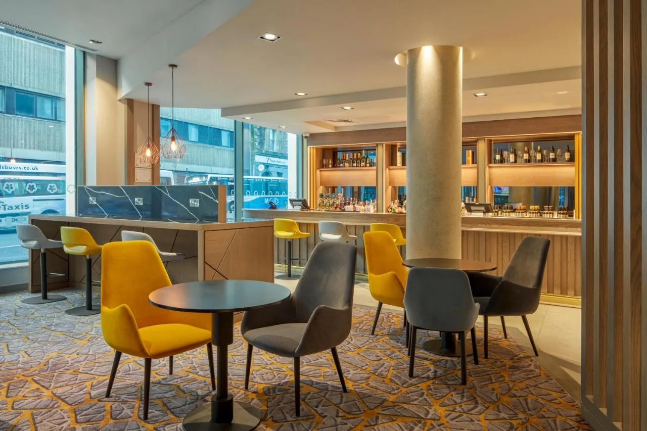 a lobby with tables and chairs and a bar at Maldron Hotel Glasgow City in Glasgow