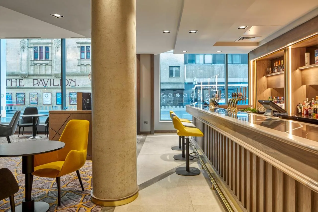 a restaurant with yellow chairs and a bar at Maldron Hotel Glasgow City in Glasgow